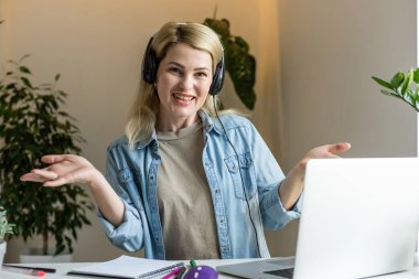 İnternette toplantı. Kulaklık takan genç bir kadın dizüstü bilgisayar kullanarak webinar izliyor ya da web kamerasıyla görüntülü konuşma yapıyor. İş konferansı. E-öğrenim eğitim kavramı.