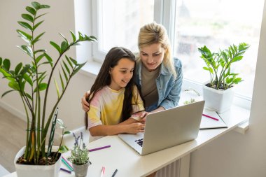 Küçük having oyunculuk online uygulama ile video çizgi film izlerken veya dizüstü bilgisayarda birlikte oyun oynayan çocuk kızı, Genç çocuk bakıcısı veya bilgisayar kullanmak için kız çocuk öğretim dadı ile mutlu anne.