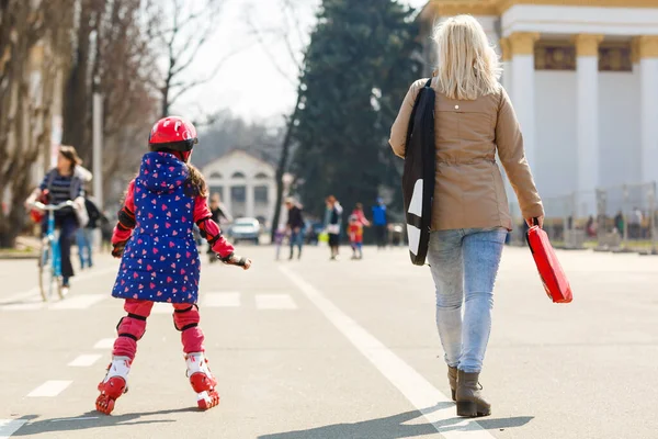 Caucasian woman teaches her daughter to skate on roller skates.