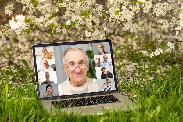 Online Group Videoconference On Laptop in a flower garden.