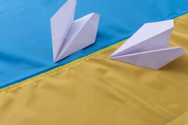 Ukrayna bayrağının arka planında kağıt uçak.