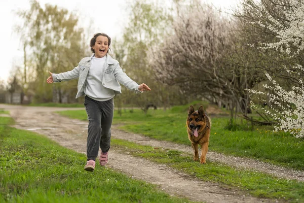 little girl running with a dog in a flower garden.