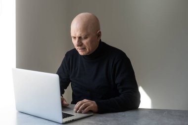 Şık giyinmiş yakışıklı yaşlı adam dizüstü bilgisayar kullanıyor..