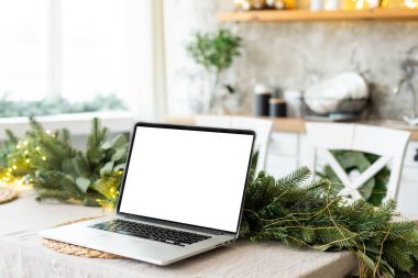Beyaz ahşap masada boş ekran dizüstü bilgisayar. Noel dekorlu, modern, rahat bir ev oturma odası. Ofis masası çalışma alanı. Kopyalama alanı oluşturun. Kış satışları, online alışveriş