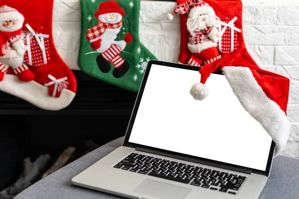 Laptop with blank screen on a desktop at home, Christmas gifts and decorations in the background.