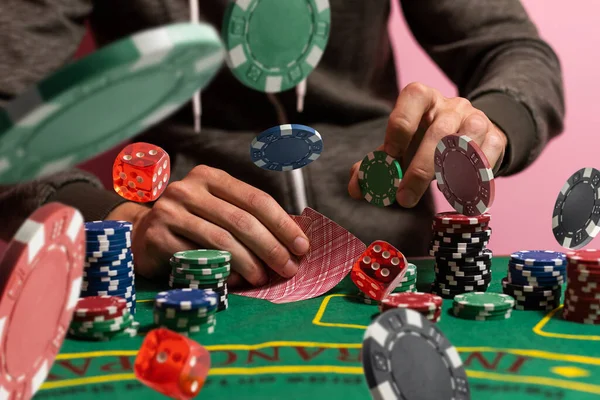 賭けのためのゲームテーブルを渡って色のポーカーチップの大規模なスタックを押すギャンブラーの男の手 — ストック写真