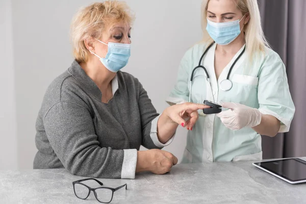 家庭健康护理 戴医疗面罩的女护士在中年妇女生病或压力时提供帮助 女医生用脉动血压计测量病人的脉搏和氧饱和度 — 图库照片