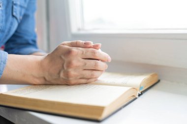 İnanç, maneviyat ve din için kutsal bir İncil üzerine dua ederken, sabahları kutsal İncil 'e dua eden bir kadın. İncil 'e dua eden kadın eli