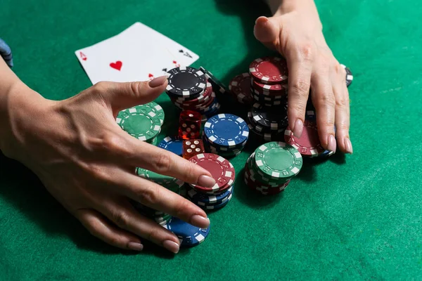 A woman plays in a casino. opening cards to raise bets. Against the background of chips. Poker victory.