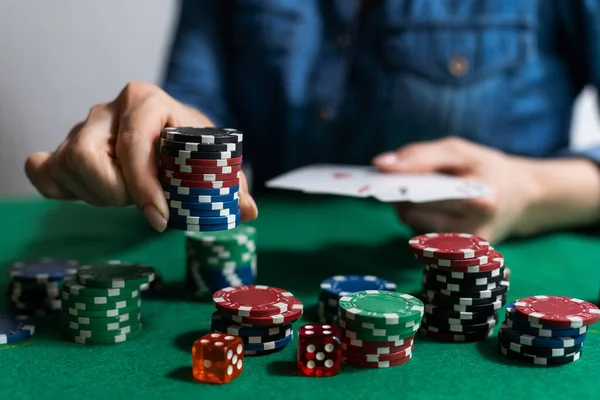 A woman plays in a casino. opening cards to raise bets. Against the background of chips. Poker victory.