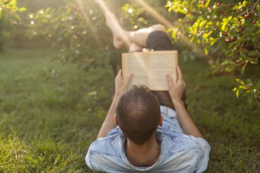 adam çimenlerin üzerine bir kitap okuma.