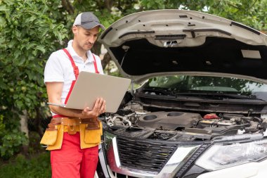 Makinist araba motoru yakınındaki dizüstü bilgisayar ile. Modern araba tanılama programı üstünde perde. Araba hizmet anlayışı.