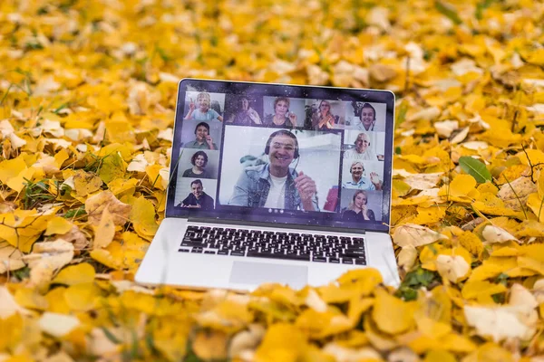 laptop with videoconference stands in the autumn park.