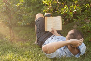 adam çimenlerin üzerine bir kitap okuma.