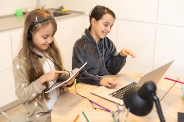 İki çocuk öğrenci birlikte video oyunu oynayarak öğretmenle çevrimiçi çalışıyor. Kardeşler Covid 19 salgınından dolayı karantina sırasında bilgisayarla evde eğitim görüyorlar.