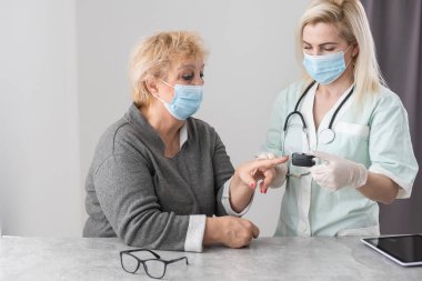 Doktor parmak ucu nabız oksimetresiyle hastayı muayene ediyor..