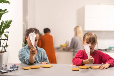 Evdeki mutfakta ev yapımı kurabiyeleri dekore eden iki kız kardeş.