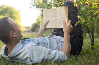 Adamın biri parkta çimlerin üzerinde İncil okuyor..