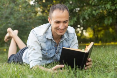 adam çimenlerin üzerine bir kitap okuma.