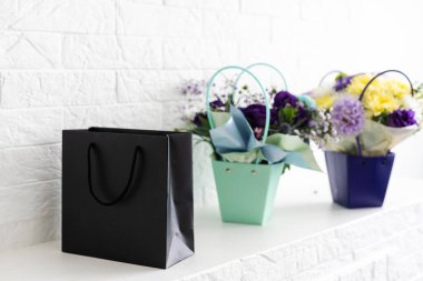 Beyaz arka planda buket ve siyah hediye çantası