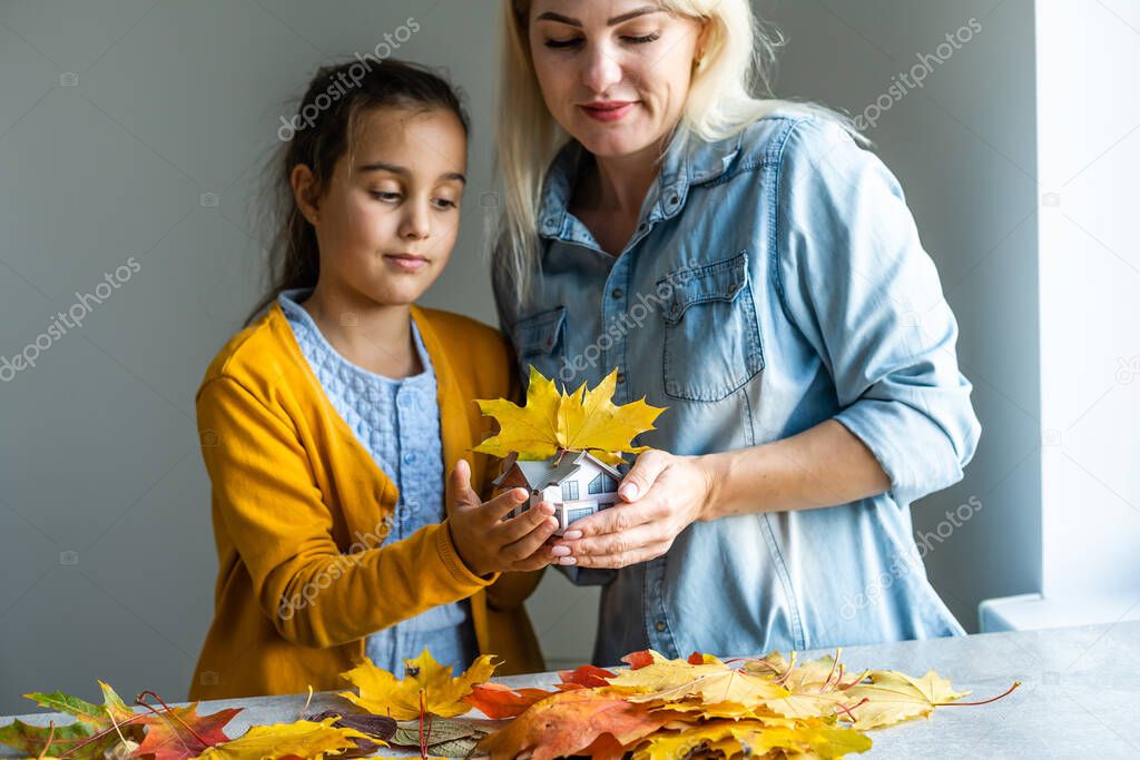Autumnal Background. Toy house and dried orange fall maple leaves. Thanksgiving banner copy space. Hygge mood cold weather concept. Hello Autumn with family.