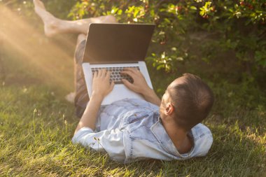 Kafkas asıllı İspanyol adam kulaklık takıyor ve çimlerin üzerinde oturup dizüstü bilgisayarla çalışıyor. Dışarıda çalışan sıradan bir adam..