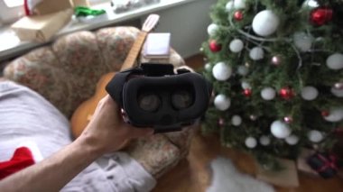 3d glasses watching virtual reality in headwear near xmas tree.