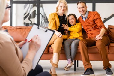 Kadın psikoloğun çocuk gelişimi sorunlarını çözmesi için genç bir aileye yardım etmesi. Aile kanepede oturuyor..