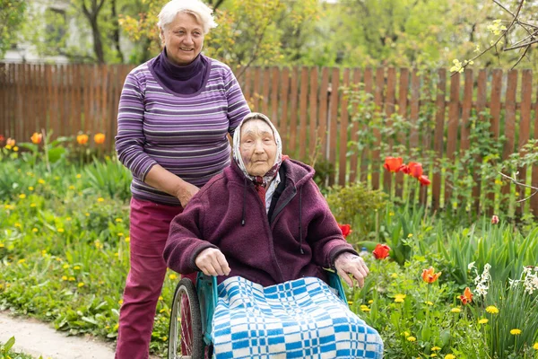 Senior care assistant with very old disabled woman in nursing home