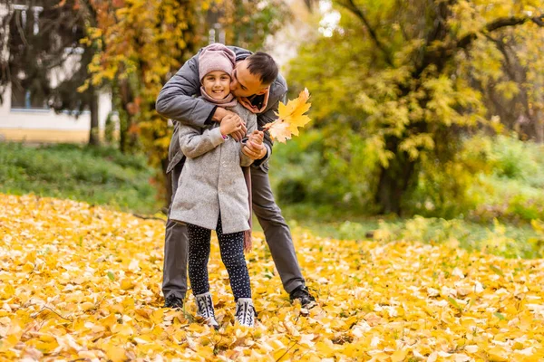 年轻的父亲和小女孩在秋天的公园里散步 — 图库照片