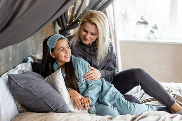 happy mother and daughter playing in bed.