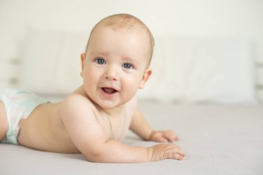Beyaz güneşli yatak odasında sevimli bir erkek bebek. Yeni doğmuş çocuk yatakta dinleniyor. Küçük çocuklar için çocuk odası. Aile sabahı evde. Yeni doğan çocuk.