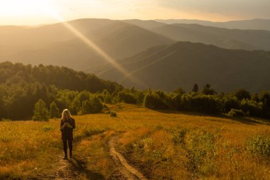 Bir kadın dağlarda yürüyüş yaptıktan sonra dinlenir..