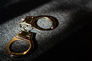 ahşap arka plan üzerinde siyah kelepçe. ceza hukuku.