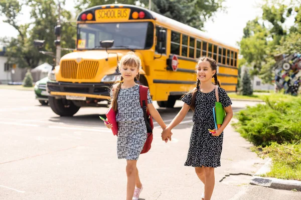 Lucky to meet each other. Cheerful smart schoolgirls. Happy schoolgirls outdoors. Small schoolgirls wear school uniform. Cute schoolgirls looking charming. Ending of school year