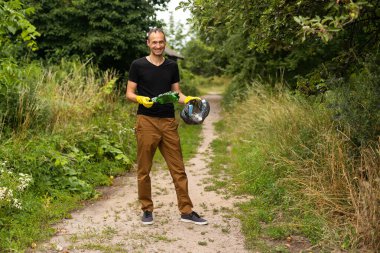 Genç gönüllü parktan plastik şişeleri topluyor..