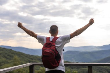 Genç adam dağın tepesindeki manzaranın tadını çıkarıyor. Karpat Dağları, Ukrayna.