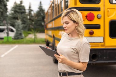 Teacher of elementary school near the school bus.