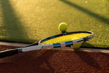Tenis raketi ve yeni boyanmış tenis kortunda yeni bir tenis topu.