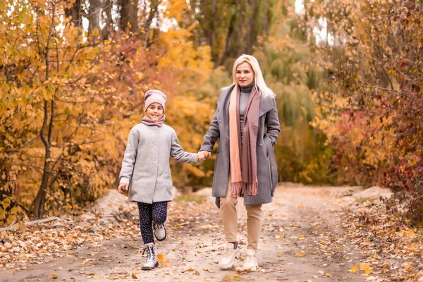 快乐的家庭母亲和孩子的女儿在秋天散步时嬉笑着玩耍 母子关系 时尚的母亲和女儿 穿着同样的外套 看起来很时髦 — 图库照片
