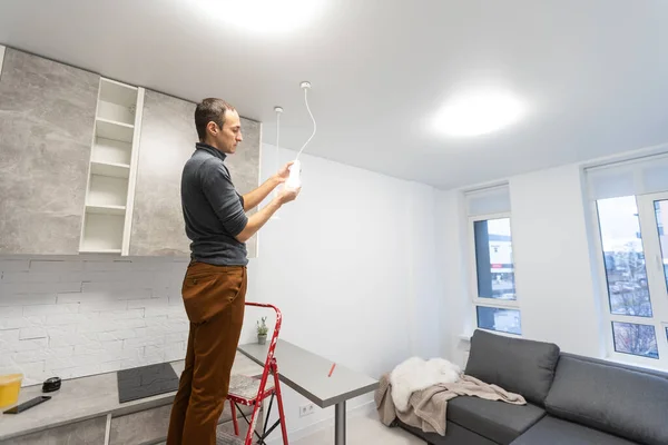 Caucasian repair master electrician man standing in apartment at stepladder.