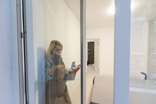 Housewife sprays the detergent on the window and wipes the window with a clean microfiber cloth. Clean transparent windows without streaks. Woman Cleaning House concept