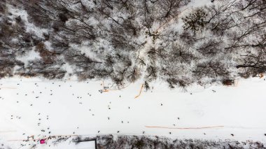 Kayak merkezindeki yamaçta İHA görüntüsü. Orman ve kayak pisti havadan. İnsansız hava aracının kış manzarası. Kayak merkezindeki karlı manzara. Hava fotoğrafçılığı.