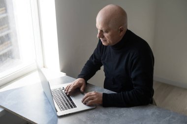 Şık giyinmiş yakışıklı yaşlı adam dizüstü bilgisayar kullanıyor..