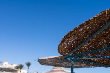 Mavi gökyüzü ile hasır plaj şemsiye