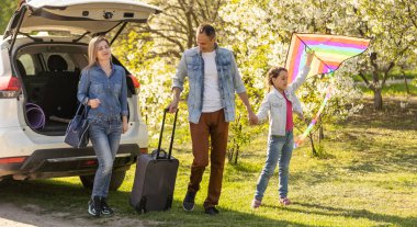 Family Enjoying. happy little girl with family near the car. Car insurance concept.