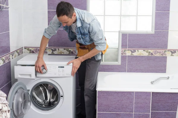 man repairs a washing machine.