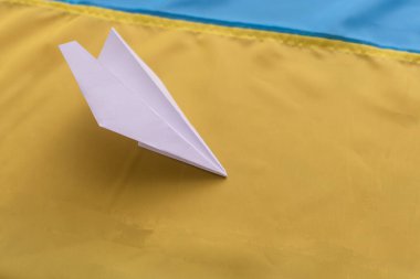 Ukrayna bayrağının arka planında kağıt uçak.