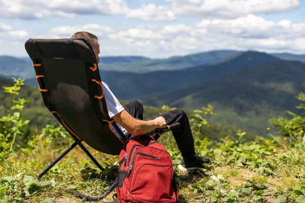 a man on a chair in the mountains.