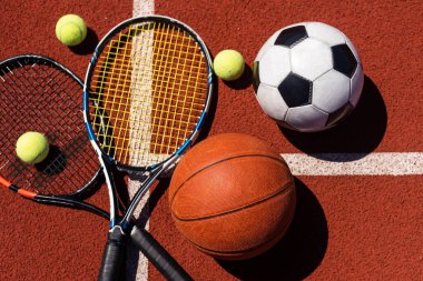 A group of sports equipment on black background including tennis, basketball, and soccer and boxing equipment on a background with copy space.